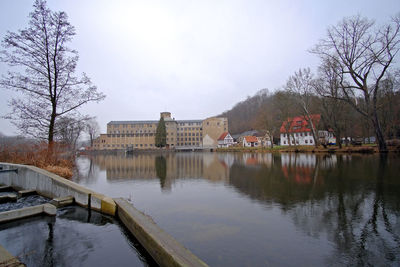 Buildings by river against sky during winter