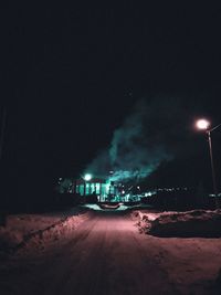 Illuminated city street against sky at night