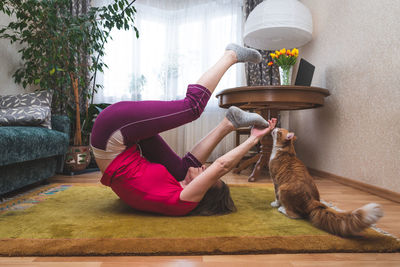 Midsection of woman relaxing by plants against wall