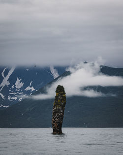 Stack rock in sea with mountains in background
