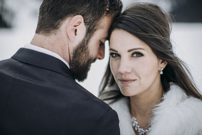 Bride and groom touch foreheads after getting married in winter on ice