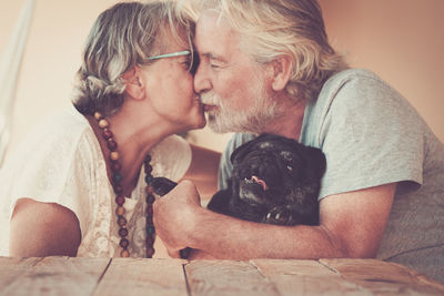 Close-up of senior couple embracing with dog at home