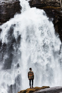 Rear view of man standing against waterfall