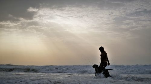 Man playing with dog in sea at beach