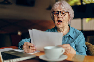 Smiling senior woman reading document at cafe