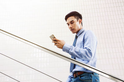 Young man using mobile phone on escalator