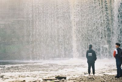 Rear view of people walking on snow covered landscape during rainy season