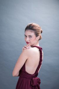 Portrait of young woman standing against gray background