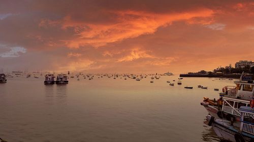 Boats in sea against orange sky
