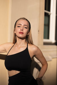 Portrait of young woman standing against wall