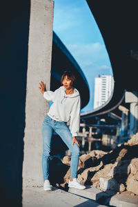 Young woman standing under bridge