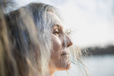 Close up woman with half closed eyes and silver hair falling on face portrait picture