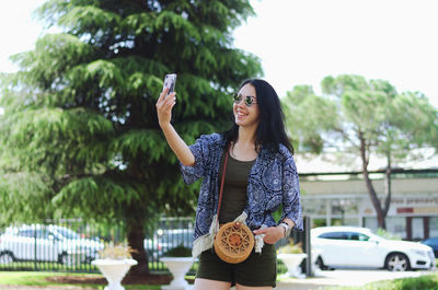 Young happy business woman relaxing in city, park. using phone. selfie. technology. summer vacation