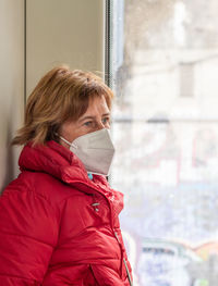 Side view of young woman standing against wall
