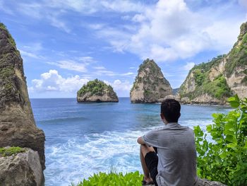 Rear view of man looking at sea against sky