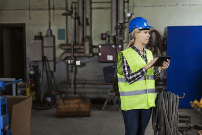 Female manual worker using digital tablet in factory