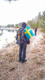 Rear view of man standing by lake against sky