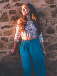 Beautiful young woman standing against wall