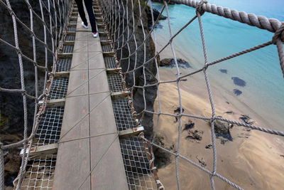 Low section of person walking on footbridge over beach