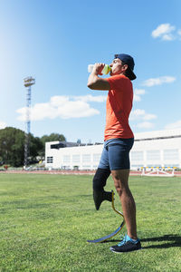 Man with prosthetic leg drinking water on running track