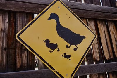 A yellow street sign with duck symbols warning of a crossing area.