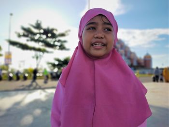 Portrait of smiling girl standing against pink background
