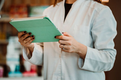 Midsection of pharmacist using digital tablet