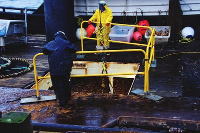 Rear view of man working at fishing ship crab unload