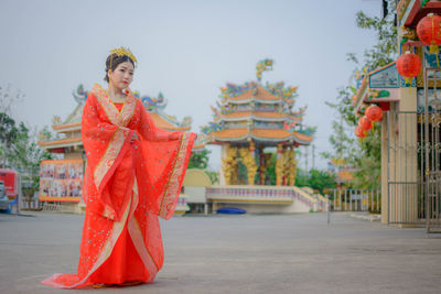 Portrait of young woman in traditional clothing standing at shrine