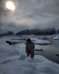 Rear view of man in snow against sky during winter