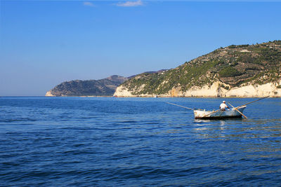 Man sailing in boat on sea against clear sky