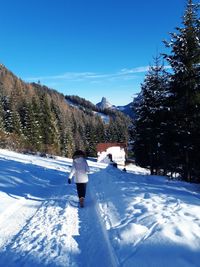 Rear view of person on snowcapped mountain against blue sky