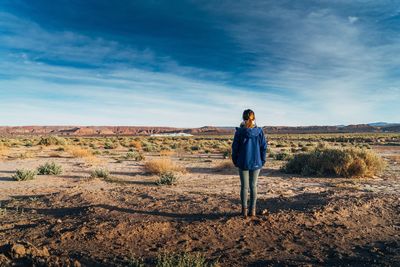 Rear view of woman standing on field against sky