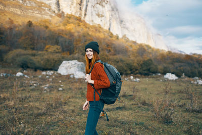 Full length portrait of smiling young woman standing on land