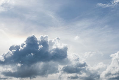 Low angle view of sunlight streaming through clouds