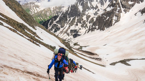 High angle view of hikers climbing snowcapped mountain