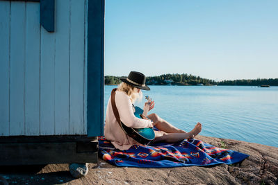 Woman sat peacefully playing the guitar at the beach on a sunny day