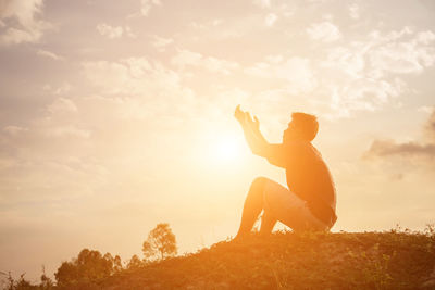 Couple kissing on field against sky during sunset