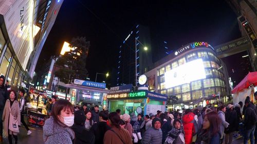 People on illuminated street amidst buildings in city at night