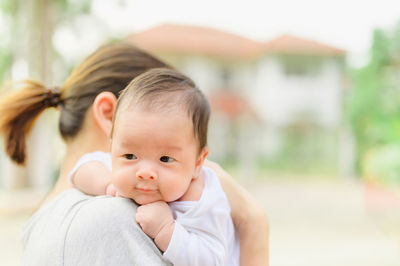 Close-up of cute baby with mother outdoors