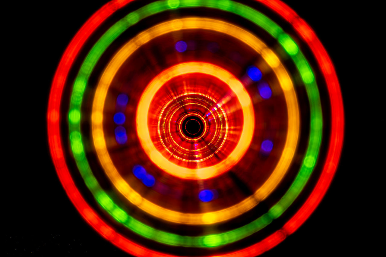 multi colored, black background, illuminated, circle, geometric shape, shape, night, toy, motion, no people, lighting equipment, light, glowing, vibrant color, concentric, studio shot, indoors, light - natural phenomenon, nightlife, sphere, spinning, technology