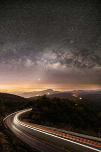Light trails on road against sky at night