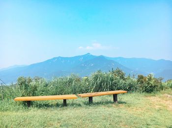 Empty park bench on field against sky