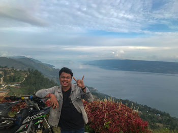 Young man standing on mountain against sky