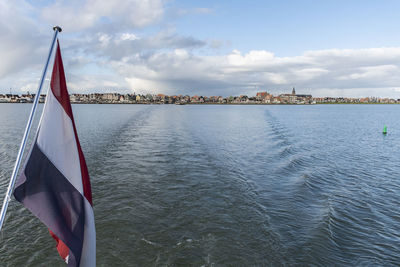 Low angle view of flag on bridge over river against sky
