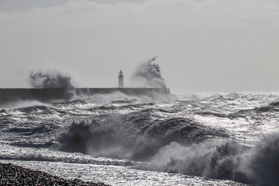 Sea waves splashing on shore against sky