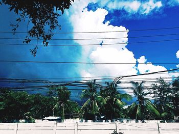 Low angle view of electricity pylon against cloudy sky