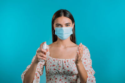 Portrait of young woman against blue background