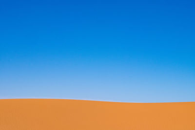 Scenic view of desert against clear blue sky