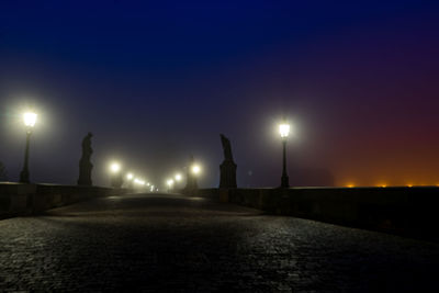 Illuminated street lights against clear sky at night